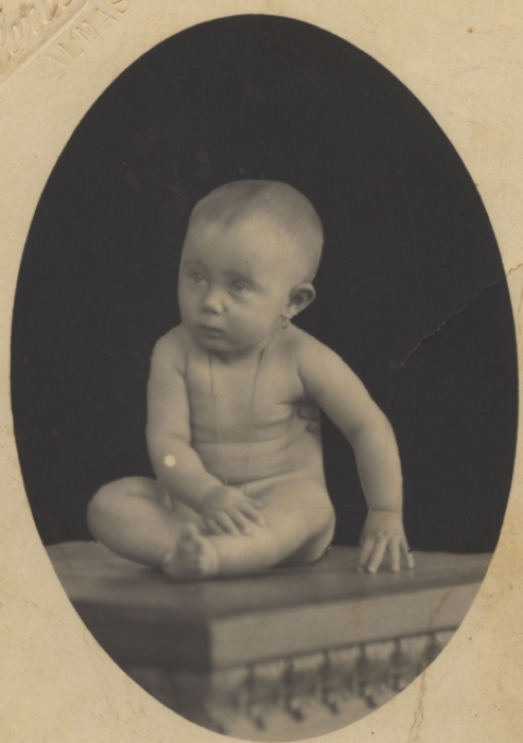 NIÑO DESNUDO SENTADO EN UNA MESA