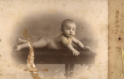 RETRATO DE BEBE DESNUDO TUMBADO SOBRE UNA MESA